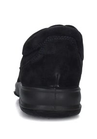 Scarpa sportiva nera in suede con un retro arrotondato, cuciture minime e suola in gomma nera texturizzata per aderenza e supporto.