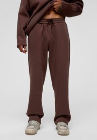 Donkerbruine sweatpants van zacht materiaal, met een elastische tailleband met een trekkoord en een comfortabele, rechte pasvorm.