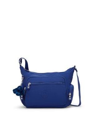 Sac bandoulière bleu avec plusieurs poches zippées et une sangle réglable, avec un petit porte-clés en peluche attaché.