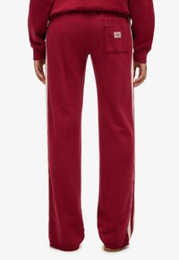 Røde sweatpants med en afslappet pasform, der har en baglomme og kontrastfarvede sidestrimler. Fremstillet af blødt bomuld. Ribstrikkede ankelmanchetter.