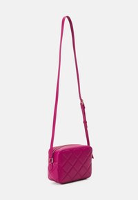 Růžová prošívaná crossbody taška s obdélníkovým tvarem, hladkým povrchem, tenkým nastavitelným popruhem a zlatým zipem.