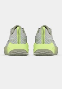 Graue Sportschuhe mit einer strukturierten Oberseite, die einen leuchtend gelben Absatz und Rückendetails aufweisen, konzipiert für Komfort und Stabilität.