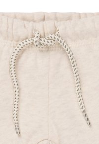 Ecrufarbene Stoffshorts mit einem elastischen Bund und einem weiß-grünen, gestreiften Kordelzug, der vorne zu einem Knoten gebunden ist.