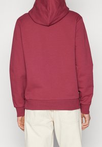 Bordowa bluza z dużym kapturem, żebrowanymi mankietami i dołem. Wykonana z miękkiego materiału, charakteryzuje się minimalistycznym wzornictwem bez widocznych logo.