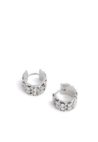 Boucles d'oreilles en argent en forme de créoles avec un design texturé présentant des motifs lisses et ondulés. Fermeture ouverte pour un port facile.