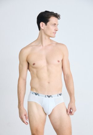 Weiße Unterhose mit einem schwarzen, gebrandeten Bund, glatter Stoff, figurnaher Schnitt und klassischem Design, auf einem Modell aus seitlicher Perspektive präsentiert.
