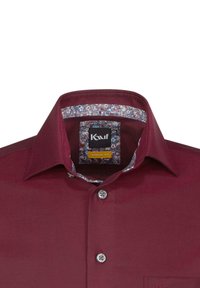 Camicia bordeaux con vestibilità moderna, chiusura a bottoni e colletto interno a fiori, con etichetta nera che mostra il nome del marchio.
