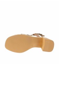 Suola di calzature realizzata in materiale gommoso beige, caratterizzata da un motivo testurizzato e un leggero tacco. Nessun accento evidente o marchio visibile.