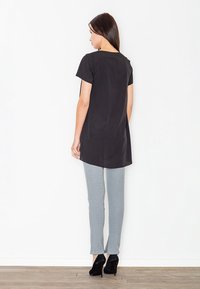 Czarna tunika z krótkim rękawem, nieco dłuższa z tyłu, zestawiona z wąskimi szarymi spodniami i czarnymi szpilkami.