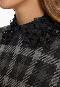 Gray knit top featuring a black collar with floral appliqué and sequins, along with a houndstooth pattern in varying shades of gray.