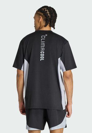 Mand med flettet hår står med ryggen til iført sort og grå ClimaCool sportstrøje og matchende shorts.