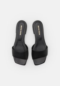 Sandalias negras de tacón con puntera cuadrada, diseño de tiras anchas, textura de cuero suave y detalles en dorado en la plantilla.