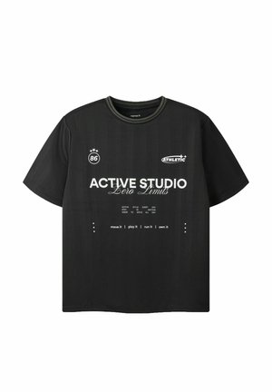 Sort T-shirt med korte ærmer med hvid tekst "ACTIVE STUDIO Zero Limits," "ATHLETIC," "86," og motiverende sætninger på fronten.
