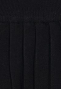 Fustă tricotată neagră cu talie elastica și design pliat. Textură moale cu un aspect uniform, potrivită pentru suprapunere sau purtare casual.