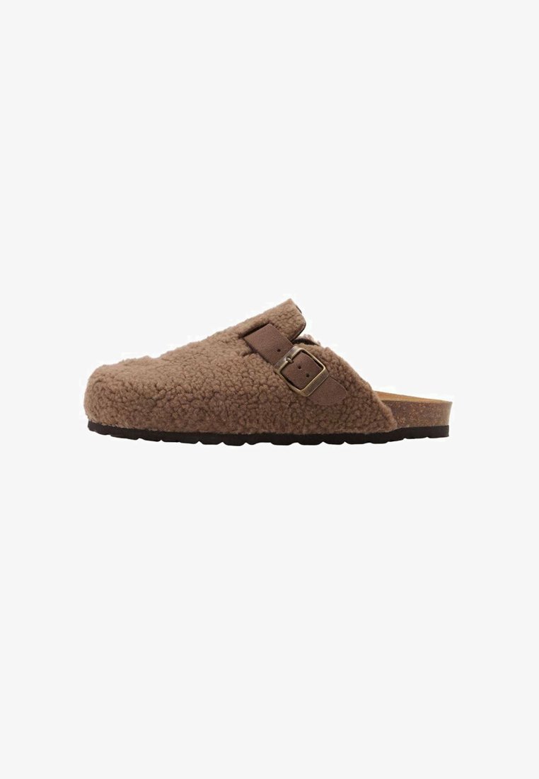 Brown shearling-lined clog with a cork footbed, featuring a single adjustable strap and a textured rubber sole for grip.
