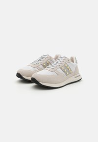 Zapatillas en gris pálido y blanco, con material de ante, acentos texturizados, tachuelas doradas en forma de corazón y suela de goma negra en contraste.