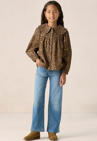 Leopard-patterned brown blouse with a large collar, paired with light blue wide-leg jeans and brown ankle boots.