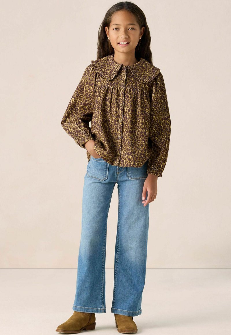 Leopard-patterned brown blouse with a large collar, paired with light blue wide-leg jeans and brown ankle boots.