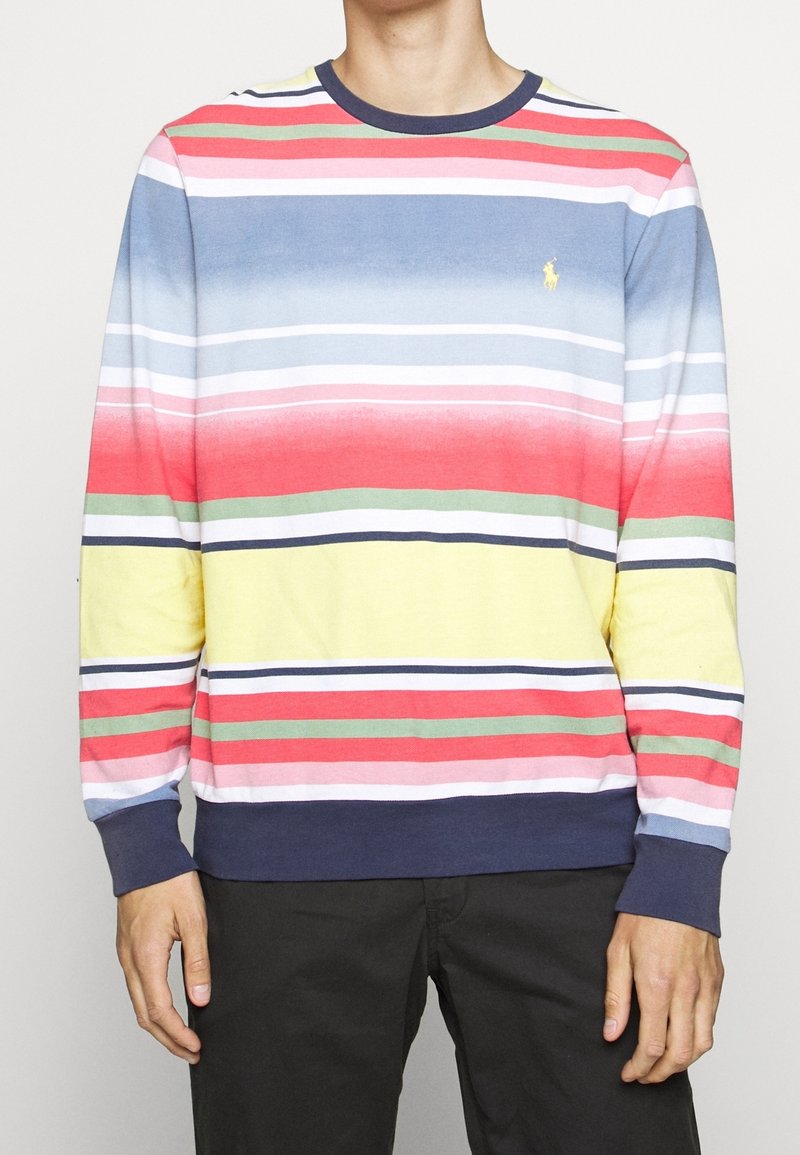Wielokolorowy, długi rękaw, sweatshirt z poziomymi paskami w kolorze czerwonym, różowym, niebieskim, zielonym i żółtym; granatowy ściągacz przy kołnierzu i mankietach.
