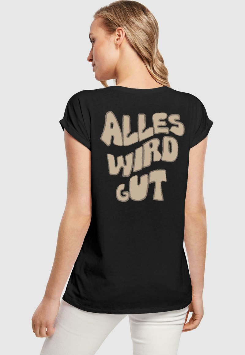 Juodas trumpomis rankovėmis marškinėliai su laisvu kirpimu, nugaroje esantis kreminis grafikos tekstas skelbia "ALLES WIRD GUT."
