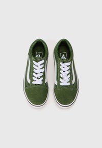 Une paire de baskets en daim vert avec des lacets blancs et des bandes latérales, vue de dessus sur un fond blanc.