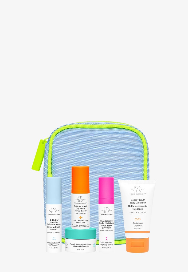 Skincare set featuring four serums and a cleanser in cylindrical and jar containers, arranged in front of a light blue pouch with neon accents.