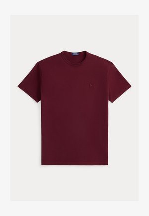 Camiseta de algodón burdeos de manga corta, con cuello redondo y un pequeño logo bordado en el lado izquierdo del pecho. Textura suave, corte clásico.