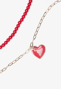 Collar de cuentas rojas con una cadena de oro. La cadena presenta un colgante en forma de corazón rojo brillante, destacando los materiales y colores contrastantes.