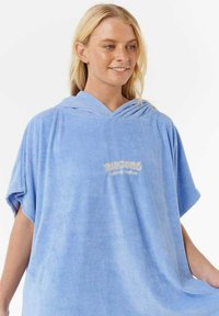 Toalla poncho azul claro hecha de un material suave y texturizado con capucha. Presenta un pequeño y sutil logotipo en la parte delantera en color crema.