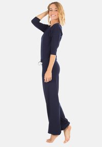 Ensemble de détente deux pièces de couleur marine comprenant un haut ajusté et un pantalon ample. Tissu doux, manches trois-quarts et taille à cordon.