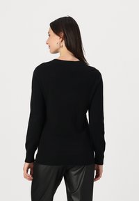 Svart genser med ribbede mansjetter og hem, rund hals og en myk tekstur. Stylet med svarte faux skinnbukser.