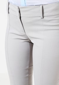 Ljusgrå skräddarsydda byxor med en slät textur. Har sidofickor och elegant sömnad, designade för en figurnära silhuett.