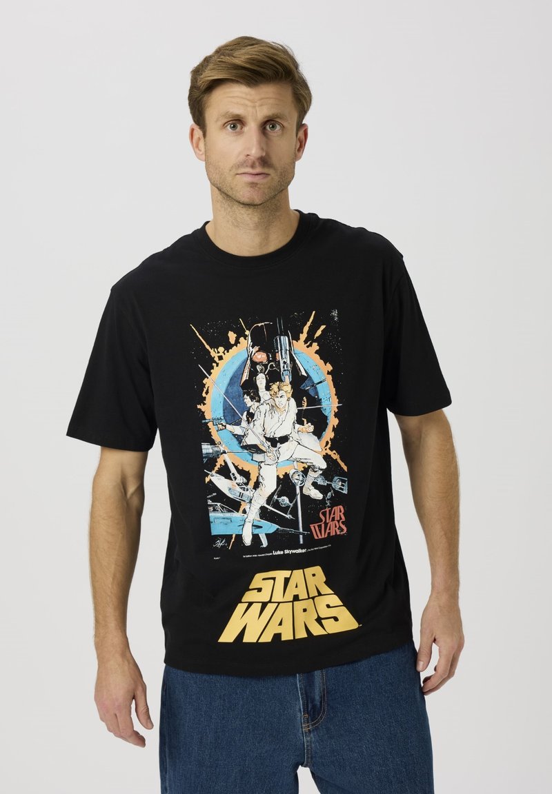 Camiseta de algodón negra que presenta una impresión gráfica colorida de personajes y naves espaciales de Star Wars, con texto amarillo en la parte inferior.