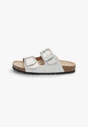 Sandalo slide bianco con due fibbie argentate regolabili, cinturini texturizzati, soletta in sughero e suola nera texturizzata, mostrato di profilo.