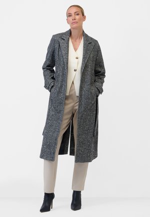 Gray textured overcoat with a notched collar, two front pockets, and a long length, paired with cream top and beige pants. Black heeled boots.