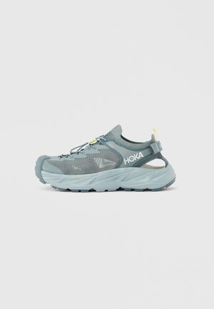 Light blue grey athletic shoe with mesh upper, reinforced toe cap, and adjustable laces. Contoured sole for comfort and grip.