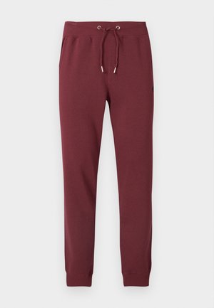 Pantalon de jogging bordeaux en tissu doux, avec taille à cordon, poches latérales, jambes fuselées et poignets élastiques.
