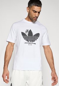 Λευκό βαμβακερό t-shirt με μεγάλη μαύρη γραφική απεικόνιση του λογότυπου τριφύλλι της Adidas με ρίγες και το κείμενο «Juventus» από κάτω.