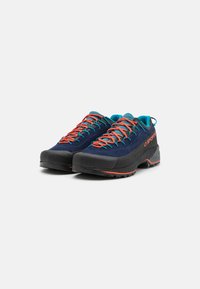Scarpe da trekking blu in pelle scamosciata con suole in gomma nera, lacci arancioni in contrasto e fodera in rete traspirante. Caratterizzate da una costruzione resistente e un grip antiscivolo.