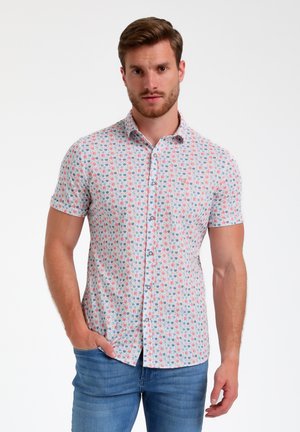 Short-sleeve button-up shirt in light blue with a colorful dot pattern. Features a spread collar and a slim fit. Paired with blue jeans.
