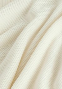 Un material textil de culoare crem, cu o textură fină și nervuri verticale, prezentând o suprafață moale și netedă. O strălucire subtilă este vizibilă în pliuri.