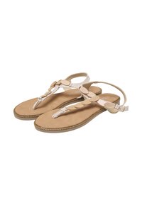 Beige flade sandaler med remme og guldfarvede ovale pyntedetaljer, ankelspænder og syninger langs kanten på lyst brune såler.