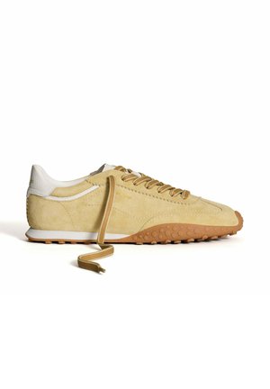 Sneakers en daim beige clair avec des accents en cuir blanc, bout rond et semelle en caoutchouc texturé. Dotés de lacets beiges et d'un col rembourré.