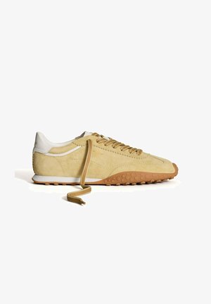 Suède sneakers in lichtbeige met witte leren accenten, ronde neus en een getextureerde rubberen buitenzool. Bevat beige veters en een gevoerde kraag.