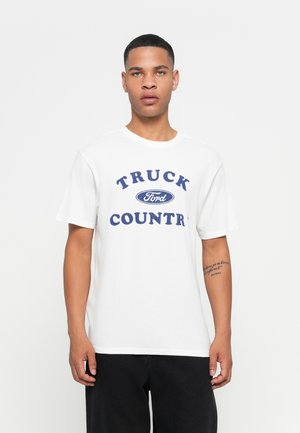 White cotton t-shirt featuring blue "TRUCK FORD COUNTRY" text. Short sleeves, crew neck, and relaxed fit. Plain design with no patterns.
