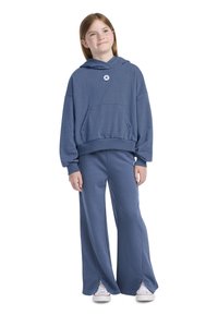 Hanorac albastru cu buzunar frontal și logo, asociat cu pantaloni largi asortați. Material moale, croială lejeră și manșete ribbed pentru confort.