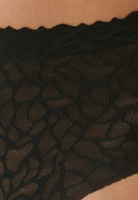 Czarne koronkowe bielizna z teksturowanym siateczkowym wzorem, falbaniastymi brzegami i misternymi kwiatowymi zdobieniami. Lekki i półprzezroczysty materiał.