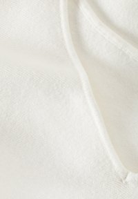 Witte hoodie stof met een zachte textuur, voorzien van subtiele ribbels en een zichtbare koord. De gestikte randen zijn schoon en netjes.