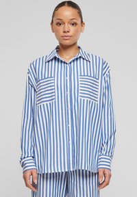 Camicia a maniche lunghe a righe blu e bianche con due tasche, colletto e vestibilità comoda. Tessuto morbido.