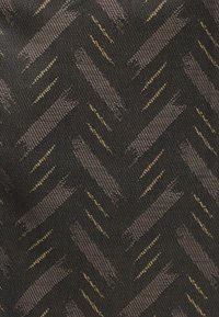 Μαύρο ύφασμα με διαγώνιο σχέδιο ψαροκόκκαλο σε σκούρο γκρι και διακριτικές λεπτές χρυσές ρίγες υφαντές σε όλο το ύφασμα.